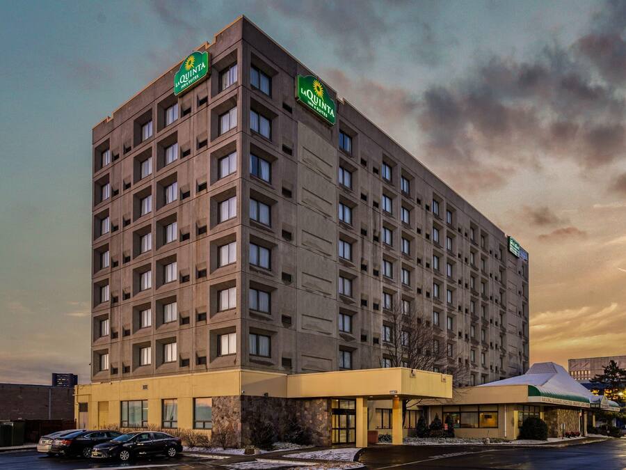 A multi-story hotel with a flat facade, numerous windows, and a green sign indicating it is a La Quinta Inn & Suites.
