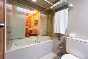 Bathroom features a glass-enclosed bathtub, toilet, and shower area in a clean, minimalist design.