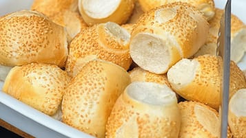 Um prato de pães de gergelim sobre um prato branco, com uma faca ao lado.