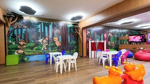 A children's play area with a mural, wooden flooring, and colorful plastic furniture. - Castro's Park Hotel (Goiania)