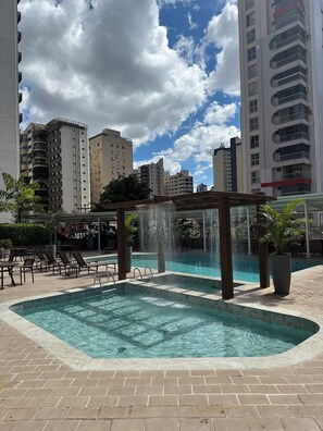 Relax by the pool surrounded by lush greenery and a soothing water feature.