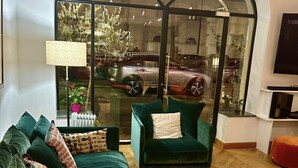 Sala de estar con un sofá verde, una mesa de centro y un amplio ventanal sobre un estacionamiento.
