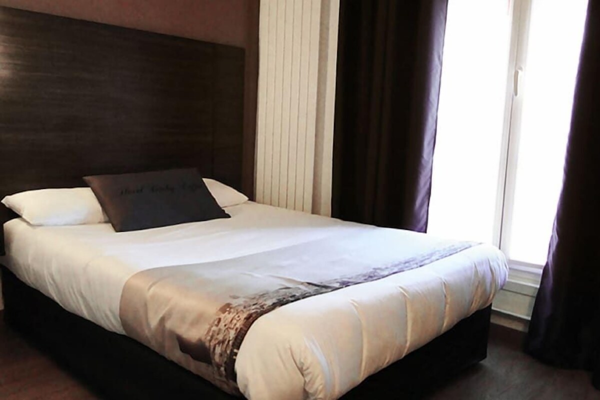 A neatly made bed with a headboard, a pillow, and a blanket.