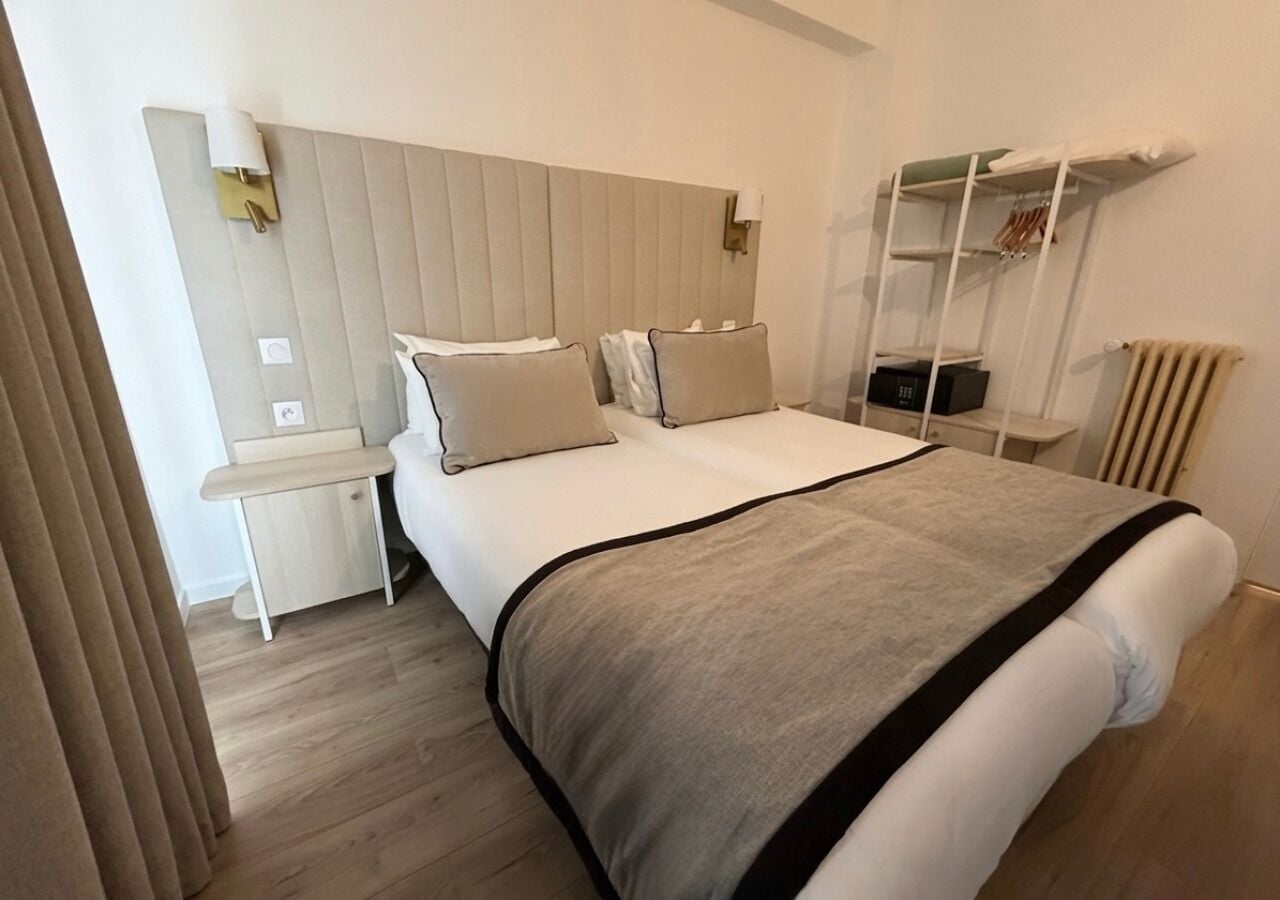 Una habitación de hotel con cama, mesitas de noche, un espejo y un armario.