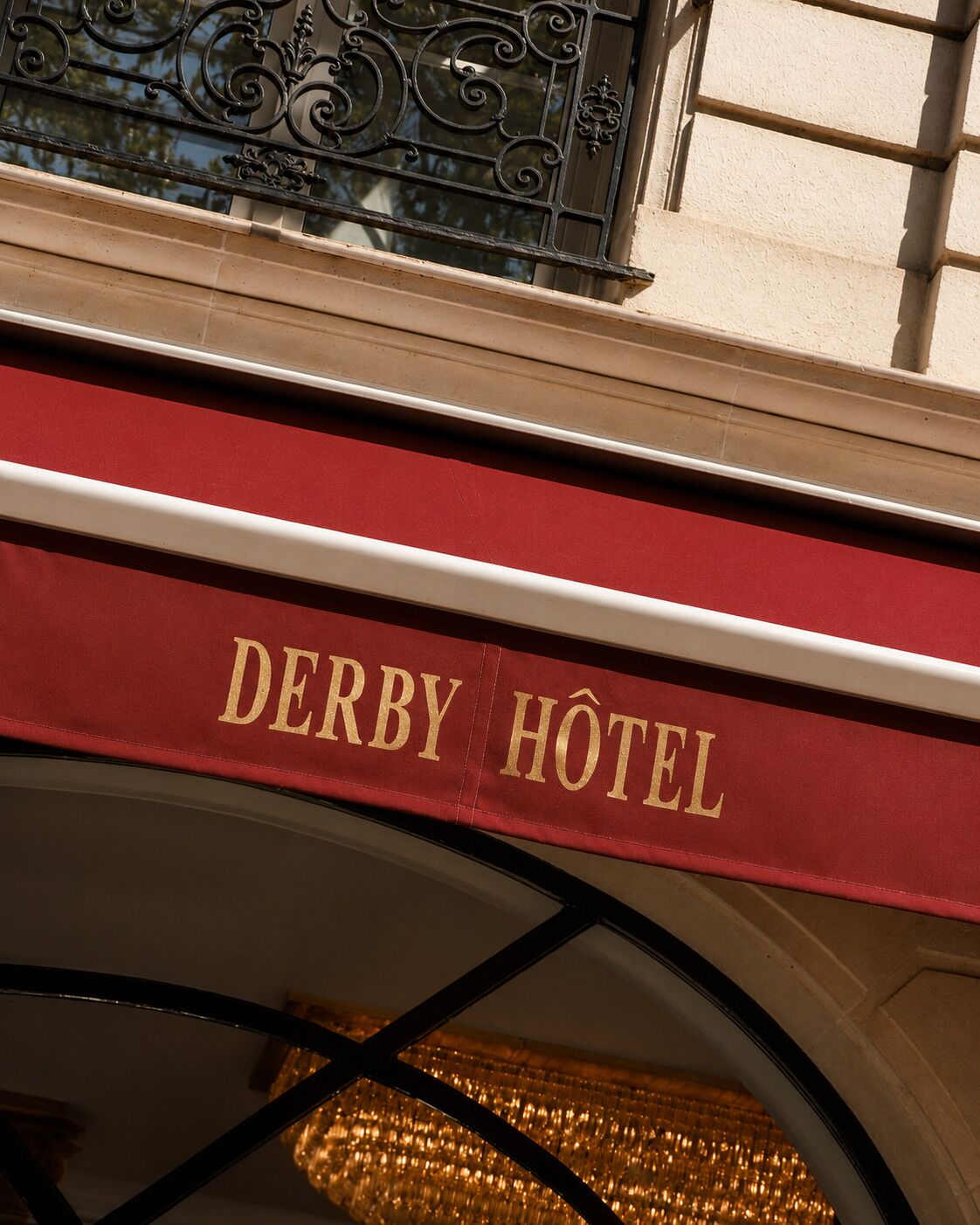 Un letrero rojo con la inscripción 'DERBY HOTEL' en letras doradas.