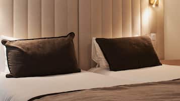 A hotel room with a large bed, two pillows, a headboard, and a wall-mounted light.