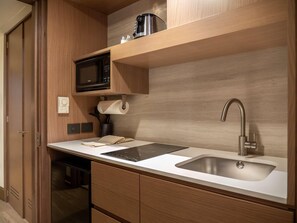 A compact kitchen with a microwave, a sink, and a paper towel dispenser. - MS Milenium Monterrey, Curio Collection by Hilton (San Pedro Garza García)