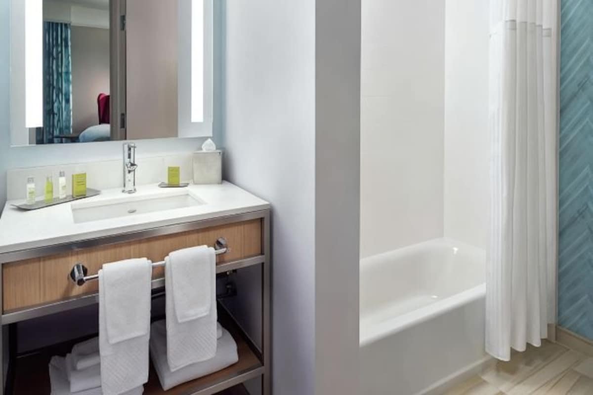 Un baño con lavamanos, espejo y bañera.