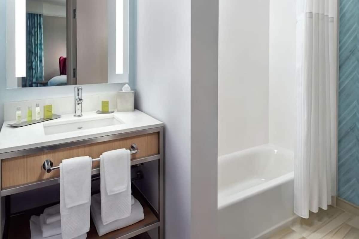 A bathroom with a sink, mirror, and bathtub.
