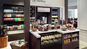 A coffee shop with a refrigerated beverage section, a coffee station, and a variety of snacks and condiments.
