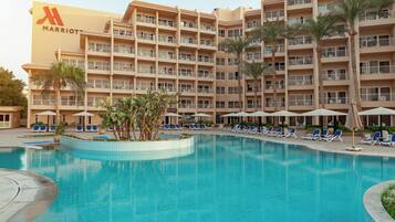 Un hotel Marriott con piscina rodeada de sillones de descanso y palmeras.