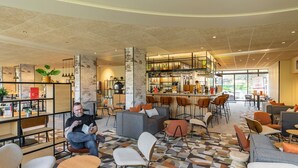 A modern lounge area with seating, a bar, and a bookshelf. - ibis Metz Centre Cathédrale (Metz)