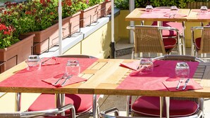 An outdoor dining area with tables and chairs, surrounded by greenery and a water feature. - ibis Metz Centre Cathédrale (Metz)