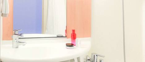 A bathroom with a white sink, a mirror, a shower, and a towel rack.