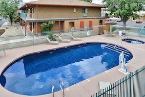 Relax by the oval-shaped pool surrounded by a green fence and lounge chairs.