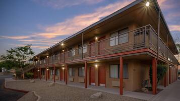 A two-story motel with a balcony on the upper floor, a covered walkway, and a gravel driveway.