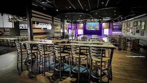 A restaurant with multiple tables and chairs, a stage with a screen, and a 'Legends' sign.