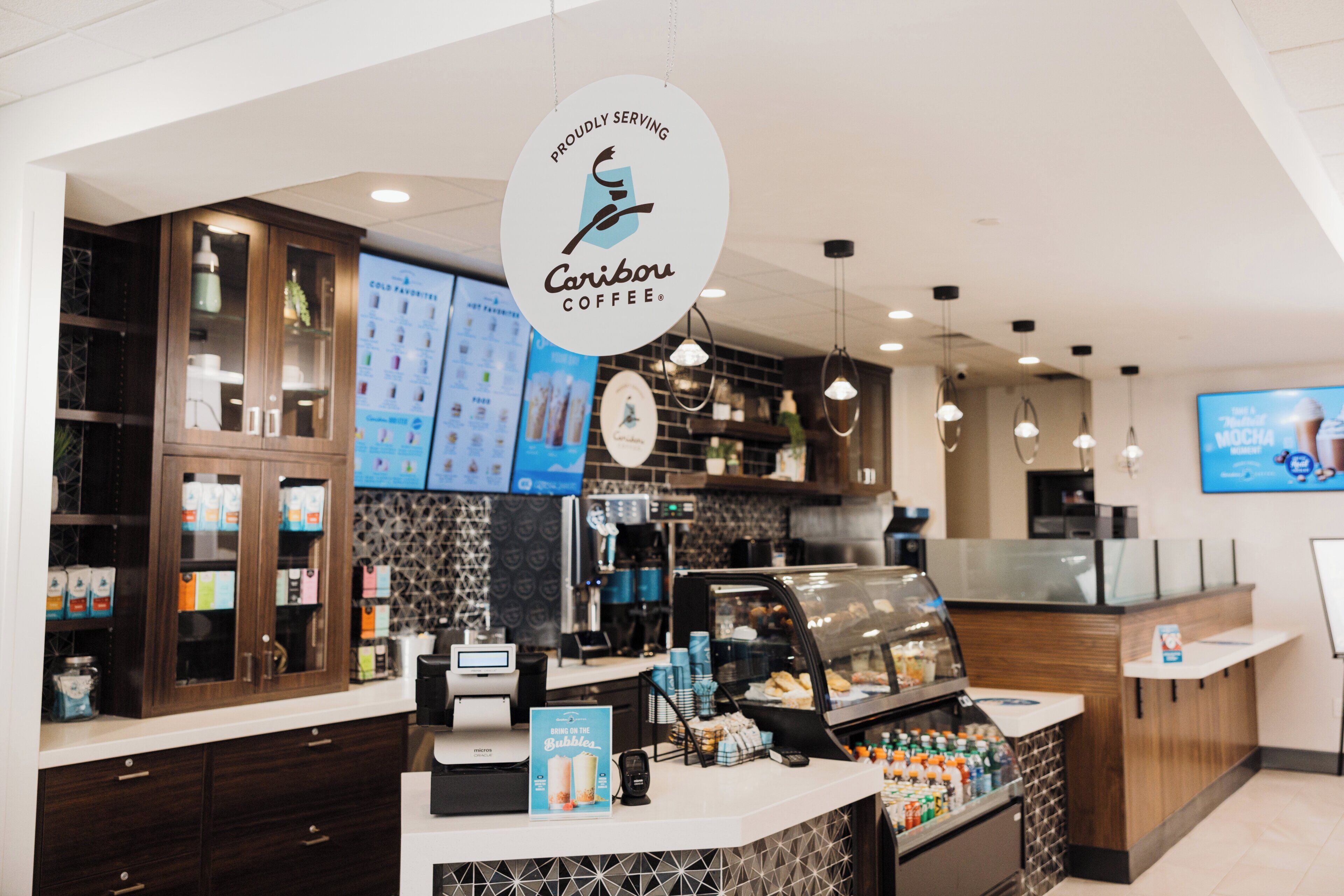 Interior d'una cafeteria amb un taulell, panells amb el menú i una màquina de cafè.