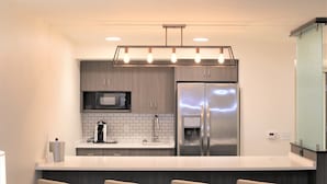 A modern kitchen with a stainless steel refrigerator, a microwave, and a coffee maker on the counter.