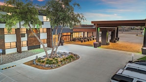 A modern building with a covered outdoor seating area and a landscaped garden.