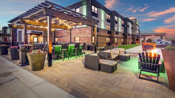 An outdoor patio area with seating, a pergola, and a brick building in the background.