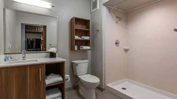 A bathroom with a toilet, a sink, a shower, and a mirror.