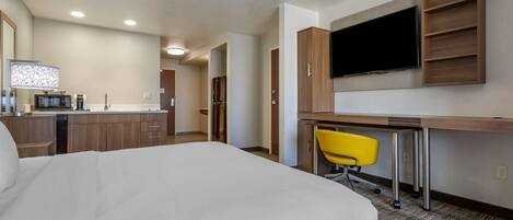 Ein Hotelzimmer mit Bett, Schreibtisch mit Stuhl, Fernseher und einer Küchenzeile.
