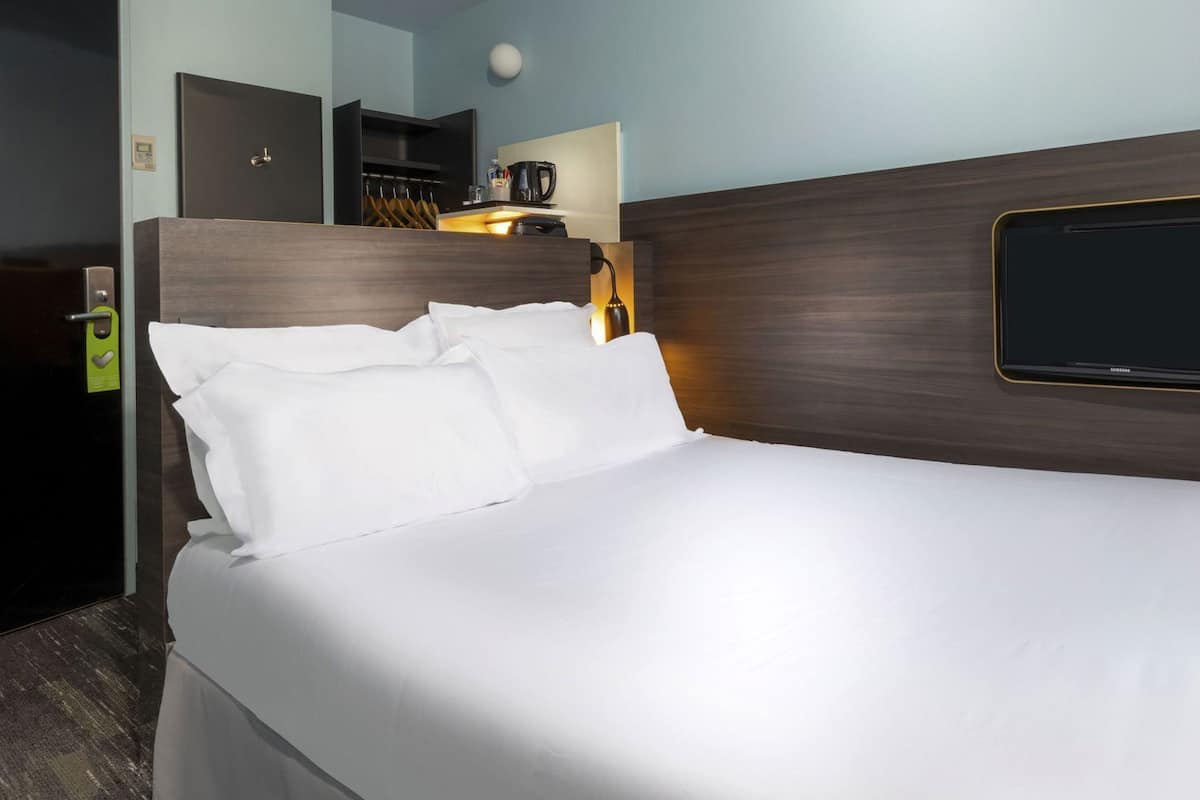Een hotelkamer met een bed, een televisie, een koffieapparaat en een kapstok.