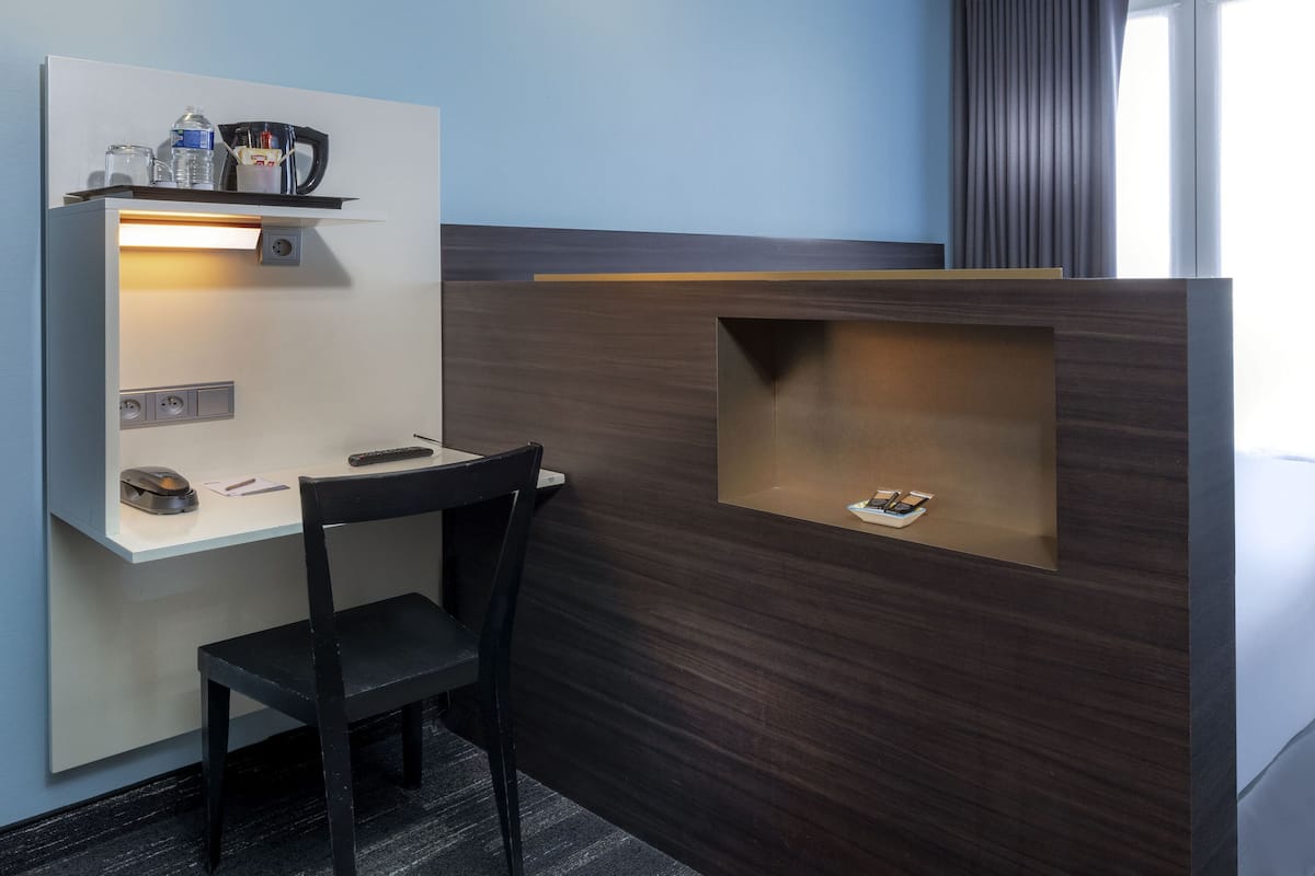Een hotelkamer met een bureau, stoel en een bed.