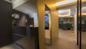 A modern reception area with a digital display, a reception desk, and a seating area with a view of the outdoors. - Libertel Austerlitz Jardin des Plantes (Paris)