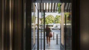A view through a glass door of a building entrance with a metal gate, a sign reading "Motel", and a street with cars and trees in the background. - Libertel Austerlitz Jardin des Plantes (Paris)
