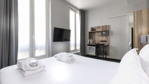 A hotel room with a large bed, a flat-screen TV mounted on the wall, a minibar, and a wooden desk with a chair. - Libertel Austerlitz Jardin des Plantes (Paris)