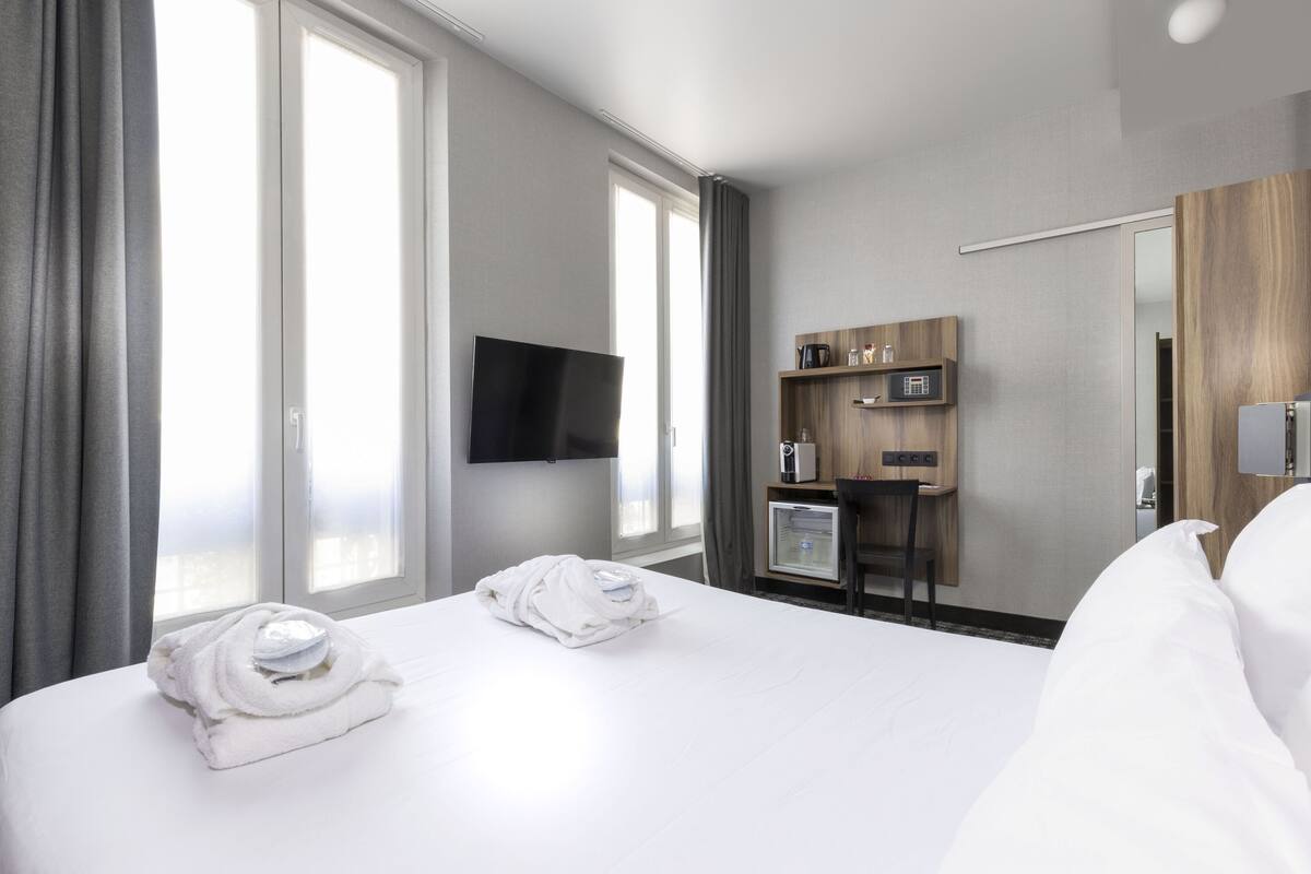Een hotelkamer met een groot bed, een flatscreen televisie aan de wand, een minibar en een houten bureau met een stoel.