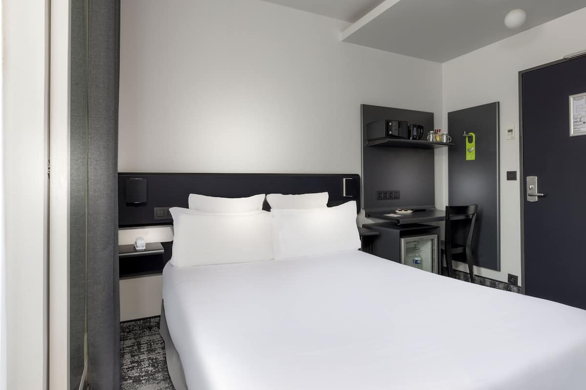 Een hotelkamer met een groot bed, een bureau met stoel, een kleine koelkast, een magnetron en een televisie.