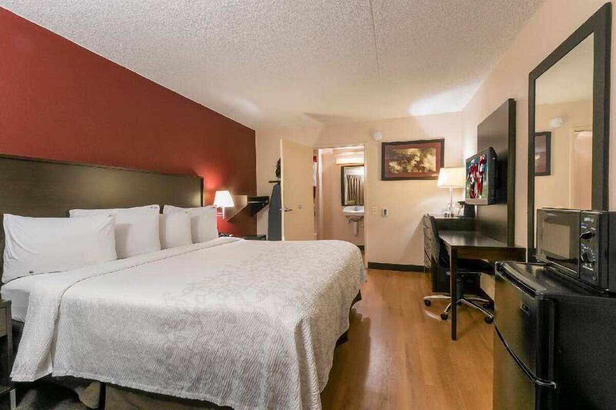 A hotel room with a bed, desk, TV, and microwave.