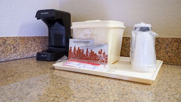 A coffee maker, a coffee pod dispenser, a water pitcher, and a coffee cup on a countertop.