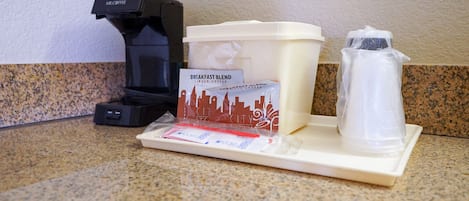 A coffee maker, a coffee pod dispenser, a water pitcher, and a coffee cup on a countertop.