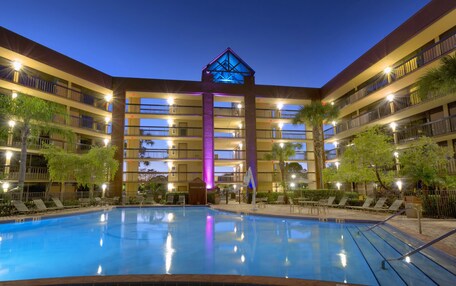 A multi-story hotel with a swimming pool, balconies, and outdoor seating areas.