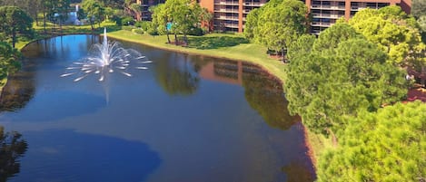 A large building with multiple floors and a courtyard with a pond and fountain.