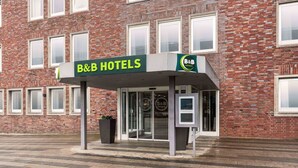 A B&B hotel entrance with a brick facade, a glass door entrance, and a small kiosk.