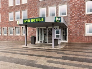 Entree van een Bed en Breakfast hotel met een gevel van baksteen, een glazen deur en een klein kioskje.