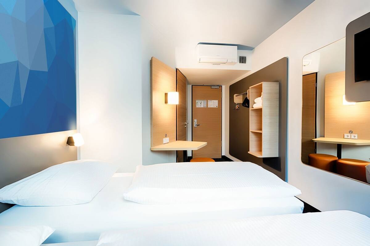 Een moderne hotelkamer met een bed, nachtkastjes, een spiegel en een wandairconditioner.