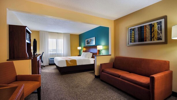 A hotel room with a bed, a sofa, a desk, and a television. - Quality Inn & Suites Bozeman (Bozeman)