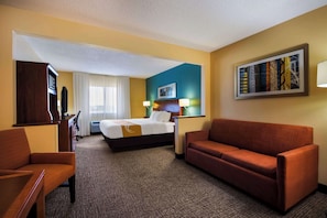 A hotel room with a bed, a sofa, a desk, and a television. - Quality Inn & Suites Bozeman (Bozeman)