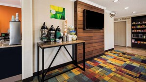 A hotel lobby with a coffee station, a television mounted on the wall, and a colorful carpet. - Quality Inn & Suites Bozeman (Bozeman)