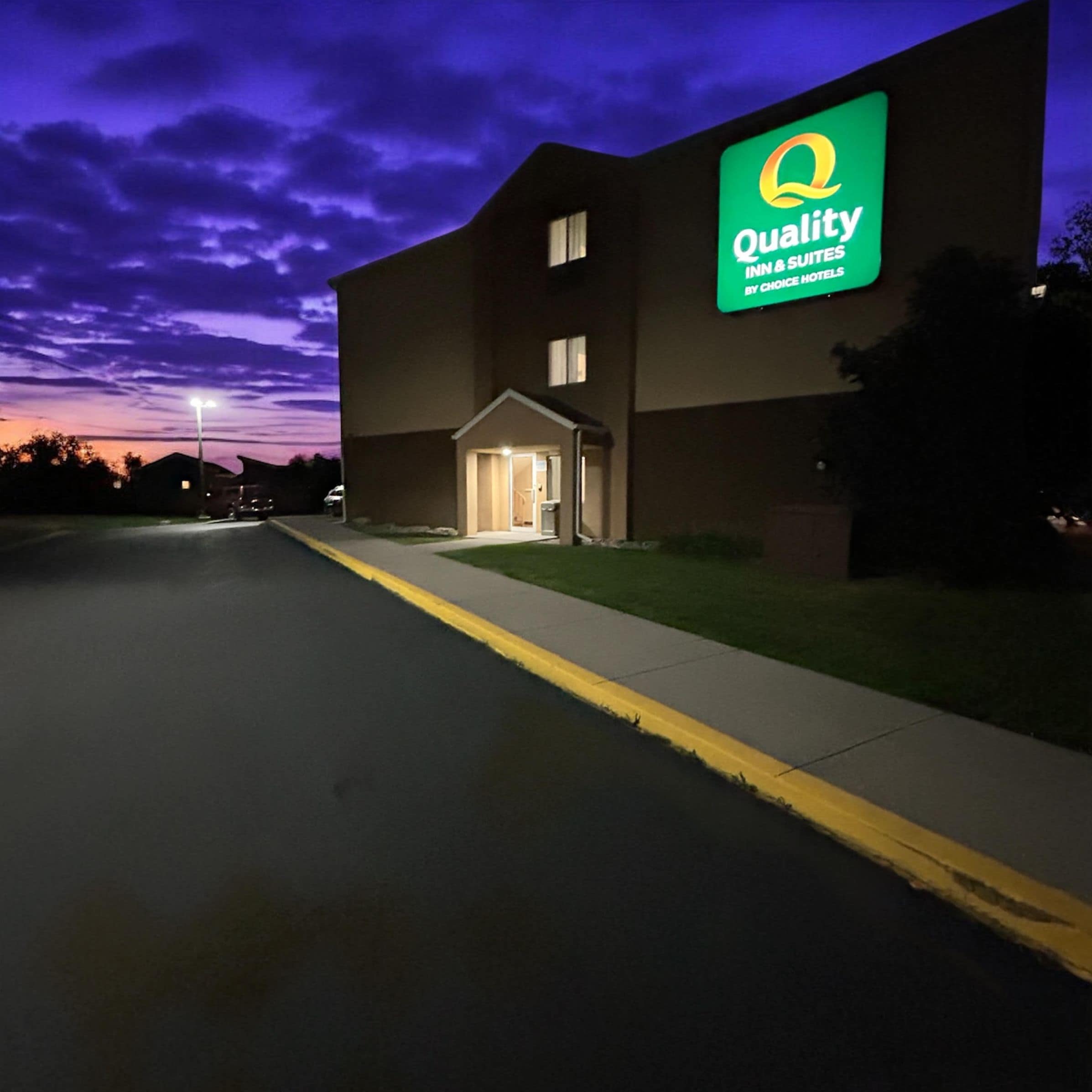 En hotellbyggnad med en stor, upplyst skylt som visar texten ”Quality Inn & Suites by Choice Hotels”.