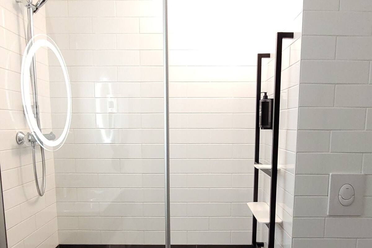Un baño moderno con ducha acristalada, lavamanos blanco y retrete.