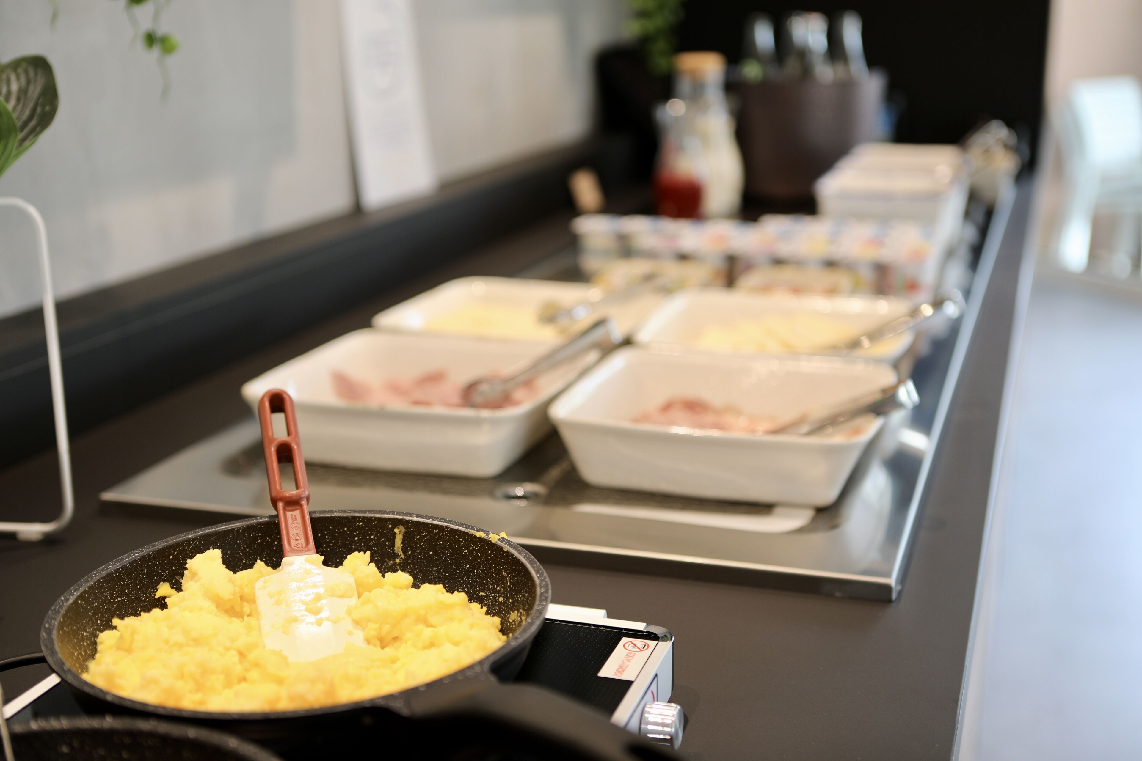En buffet med forskellige retter, herunder røræg og andre anretninger i hvide fade.