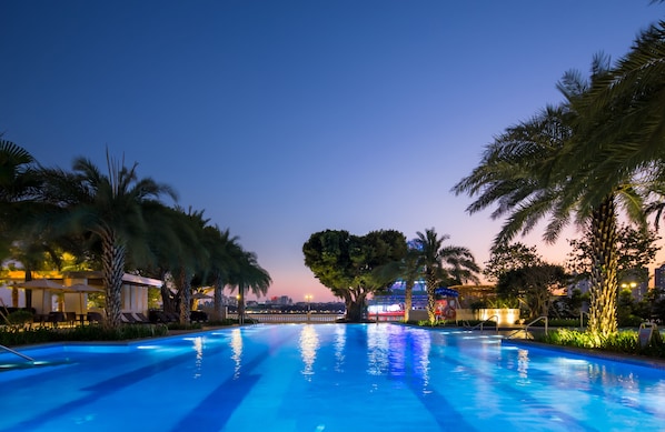 Una piscina al aire libre, sombrillas, sillones reclinables de piscina