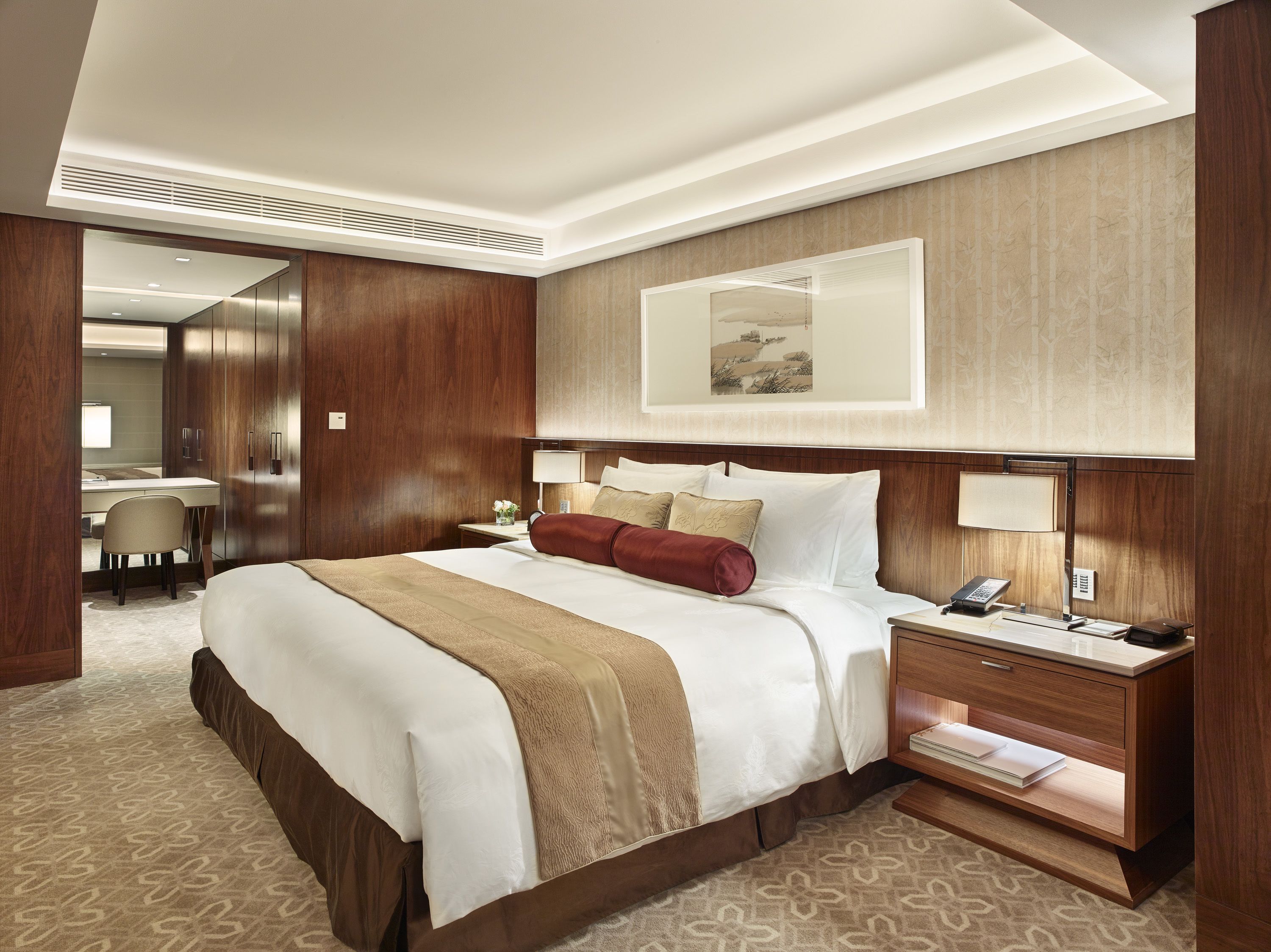 A hotel room with a large bed, a desk, a chair, and a mirror.